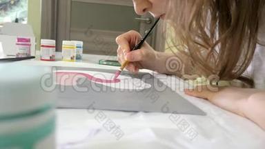坐在桌旁，一个红发的小美女用颜料和画笔作画